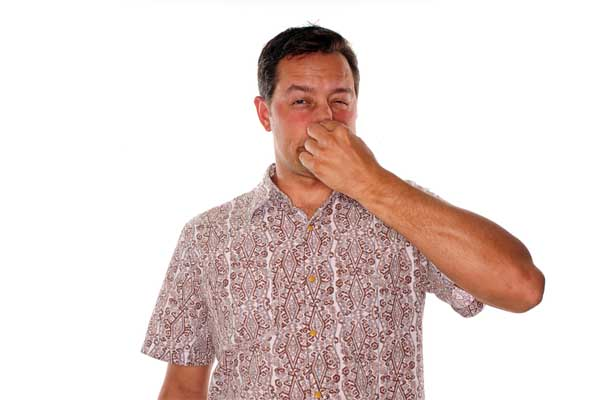 A man is shown holding his nose, indicating he smells something bad.