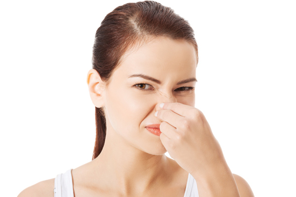 A woman is pinching her nose in distaste, indicating a bad smell. 