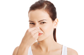 A woman pinches her nose in a gesture of distaste, likely reacting to a bad odor. 