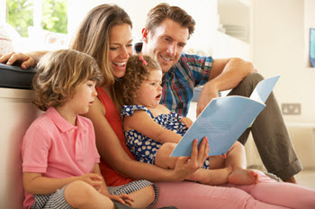 A family sits together while reading a book. 