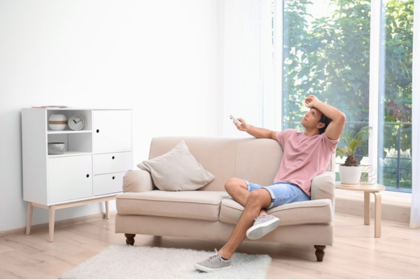 homeowner looking at air conditioning unit while holding the remote due to inefficient cooling