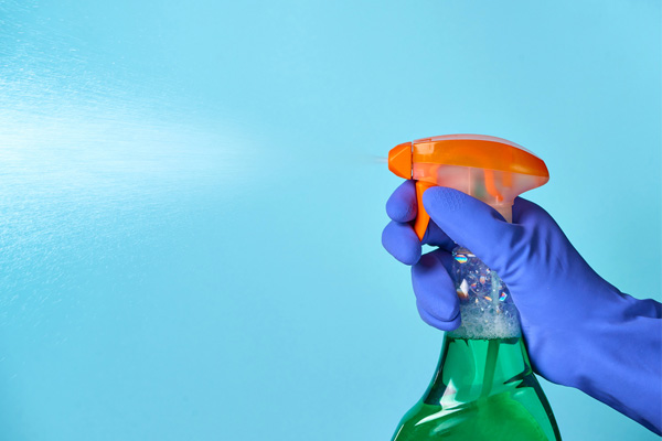 image of homeowner using disinfectant to clean