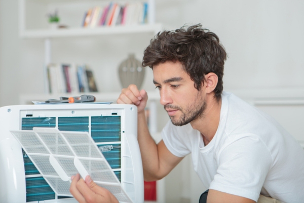 man looking at portable air conditioner filter