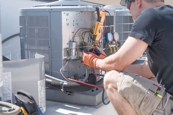 HVAC technician working on controls of air conditioner