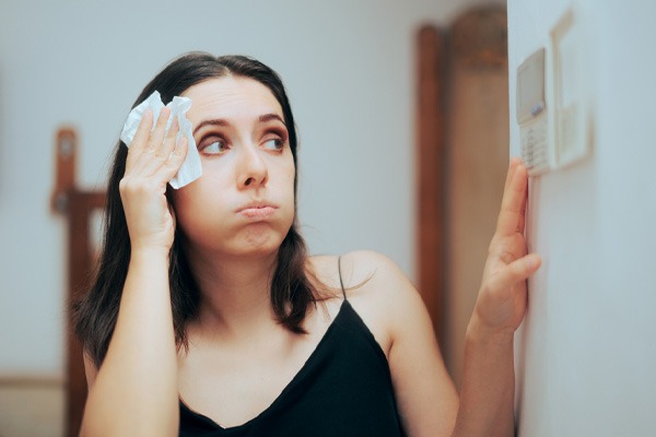 image of a homeowner looking at thermostat due to air conditioner not cooling