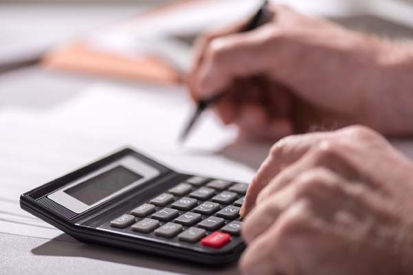 homeowner using a calculator to estimate heating oil levels in oil tank