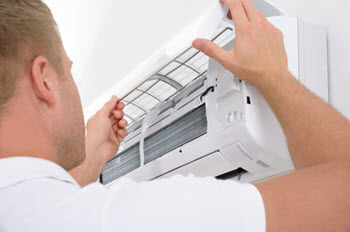 energy efficient - HVAC technician inspecting a ductless system