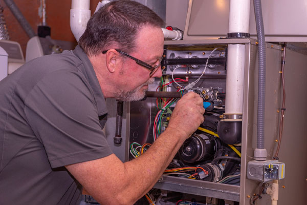 image of an hvac contractor repairing a furnace leaking water