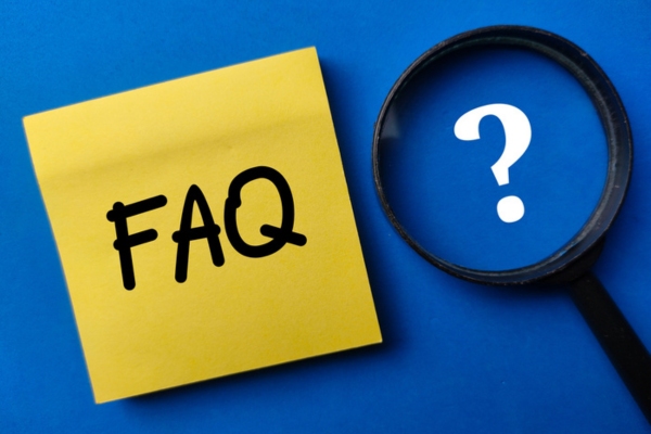 FAQ written on sticky note beside a magnifying glass enlarging question mark