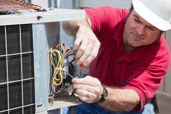 HVAC technician checking the wiring on a HVAC unit outside a home