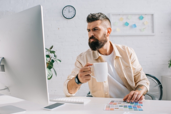 homeowner having coffee while looking at paint swatches and a computer monitor depicting the need for propane tank paint services