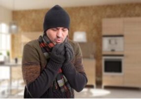 man wearing scarf & beanie indoors due to heating issues at home